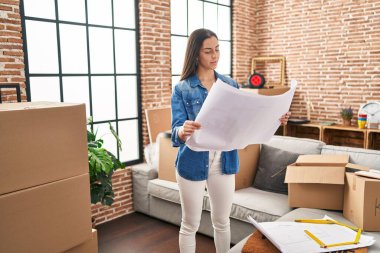 Genç, güzel İspanyol kadın mimar yeni evin planlarını okuyor.