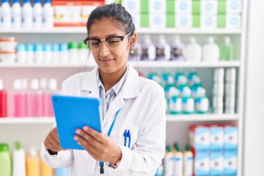 Eczanede çalışan dokunmatik ped kullanan genç, güzel İspanyol kadın eczacı.