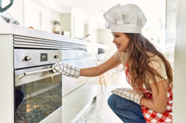 Genç, güzel, İspanyol bir kadın. Mutfakta kendine güvenen bir fırın açıyor.