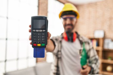 Genç İspanyol işçi gülümseyerek evde kredi kartıyla veri telefonu tutuyor.