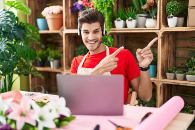 Çiçekçide çalışan genç İspanyol bir adam. Video çekiyor. Gülümsüyor ve kameraya bakıyor.. 