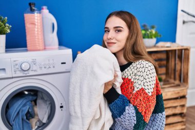 Çamaşır odasında havlu kokusu alan genç bir kadın.
