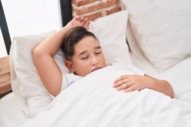 Adorable hispanic boy lying on bed sleeping at bedroom