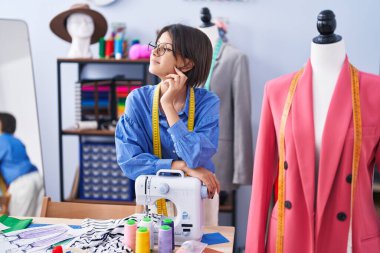 Sevimli İspanyol kız terzi gülümsüyor giyim fabrikasında dikiş makinesine yaslanıyor.