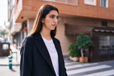 Young beautiful hispanic woman looking to the side with serious expression at street