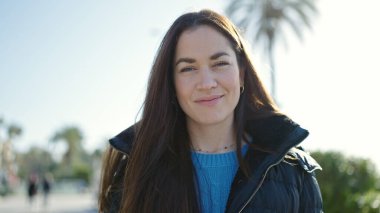 Sokakta kendine güvenen beyaz kadın gülümsüyor.