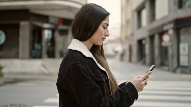 Genç ve güzel İspanyol kadın akıllı telefon kullanıyor. Sokakta ciddi bir ifadesi var.