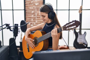 Müzik stüdyosunda klasik gitar çalan sevimli bir müzisyen kız.