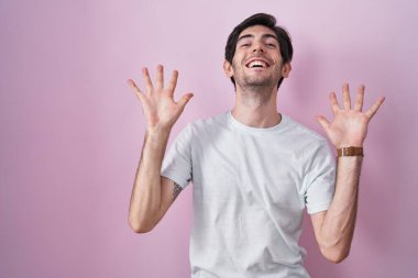 Pembe arka planda duran genç İspanyol adam çılgın ve başarıyı kollarını kaldırıp heyecanla haykırarak kutluyor. Kazanan konsept 