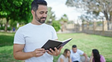 Bir grup öğrenci parkta kitap okuyor.