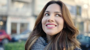 Young beautiful hispanic woman smiling confident looking to the sky at street