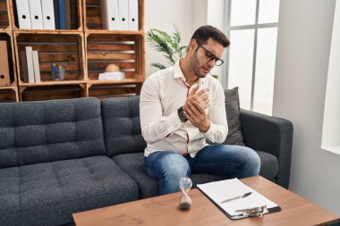 Danışma ofisinde çalışan sakallı, elleri ve parmakları ağrıyan, eklem iltihabı olan genç İspanyol bir adam. 