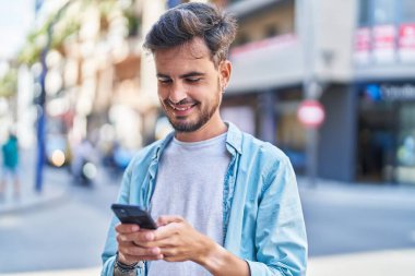 Sokakta akıllı telefon kullanan, kendine güvenen genç bir İspanyol.