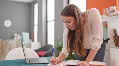 Genç ve güzel İspanyol kadın yemek odasında dizüstü bilgisayar kullanıyor.