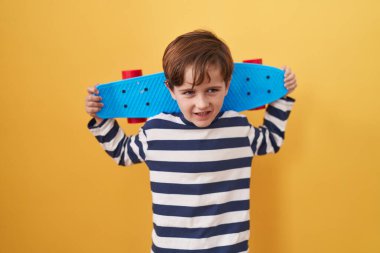 Küçük beyaz çocuk sarı arka planda paten kayıyor ve kahkahalarla gülüyor.. 