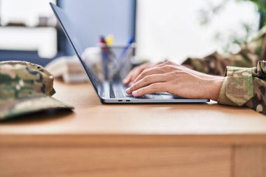 Young hispanic man army soldier using laptop sitting on table at office