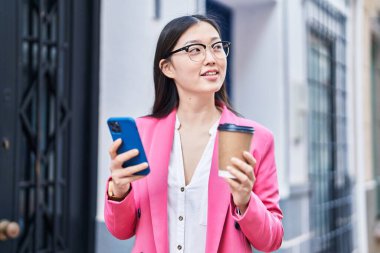 Chinese woman business worker using smartphone drinking coffee at street