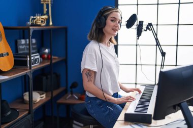 Young woman musician playing piano keyboard at music studio