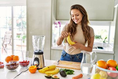 Genç, güzel İspanyol kadın mutfakta sebze suyu ve blender hazırlıyor.
