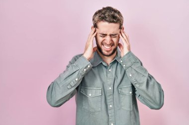 Pembe arka planda duran İspanyol sakallı adam yüksek sesli müzik sesi için kulaklarını parmaklarıyla kapatıyor. sağır kavramı. 