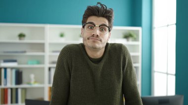 Kütüphanede rahat bir ifadeyle duran genç İspanyol öğrenci.