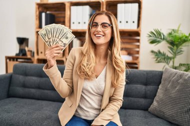 Terapi ofisinde çalışan genç sarışın kadın elinde para tutuyordu. Olumlu ve mutlu görünüyordu. Kendine güvenen bir gülümsemeyle dişlerini gösteriyordu. 