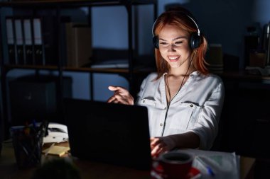 Geceleri ofiste çalışan beyaz bir kadın dostça gülümseyerek selamlama ve hoş geldin diyor. başarılı iş. 