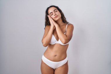 Genç İspanyol kadın beyaz iç çamaşırı giyer, uyur, yorgun düşler kurar, elleriyle poz verir, gözleri kapalı gülümserdi.. 