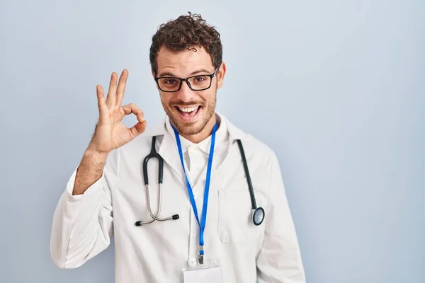 Jonge Spaanse Man Draagt Doktersuniform Stethoscoop Glimlacht Positief Doet Teken — Stockfoto