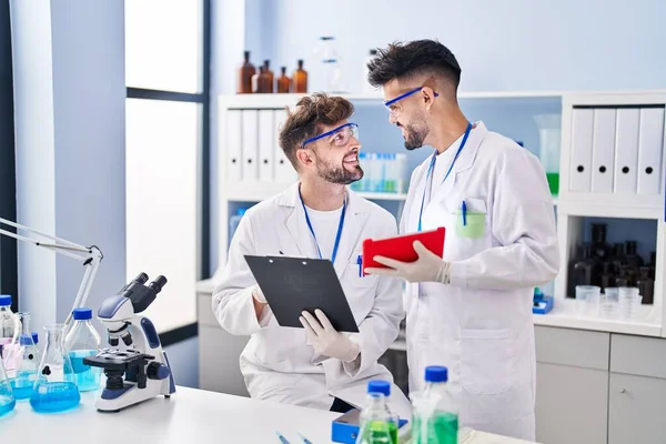Young couple wearing scientist uniform using touchpad at laboratory
