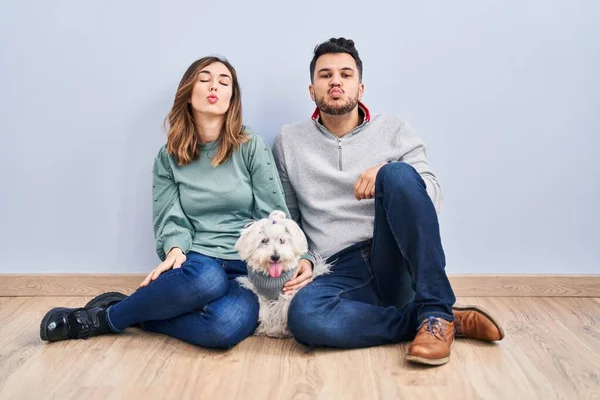 若いヒスパニック系のカップルは カメラを見て犬と床の上に座って空気中のキスを吹いて美しいとセクシーされます 愛の表現 — ストック写真
