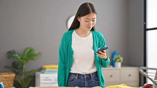 中国年轻女子在洗衣房用智能手机 — 图库照片