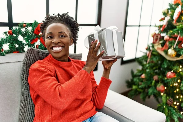 African American Woman Holding Christmas Gift Sitting Sofa Home — Stock Photo, Image