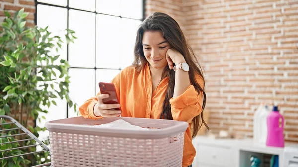 Young Beautiful Hispanic Woman Using Smartphone Hanging Clothes Clothesline Laundry — Zdjęcie stockowe