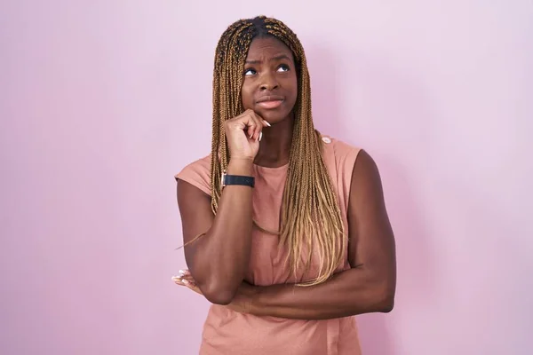 Африканская Американка Плетеными Волосами Стоящая Розовом Фоне Думающая Вопросе Обеспокоенная — стоковое фото