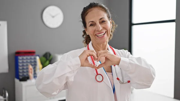 Латиноамериканка Средних Лет Доктор Улыбается Делая Сердечный Жест Руками Клинике — стоковое фото