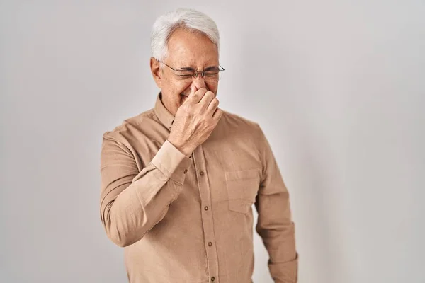 ヒスパニック系の高齢者の男性は 鼻の上に指で息を保持し 臭いと嫌な 耐え難い匂いの何かを嗅ぐ眼鏡を着用 臭いが悪い — ストック写真