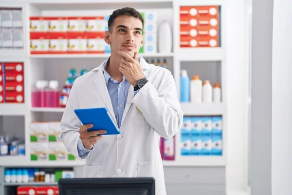 Hombre Hispano Guapo Trabajando Farmacia Con Tableta Cara Seria Pensando — Foto de Stock