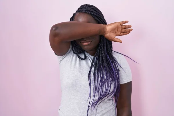 ピンクの背景に立って腕で目を覆い 真剣に悲しい顔をしている若いアフリカ人女性 目立たず隠し拒否の概念 — ストック写真