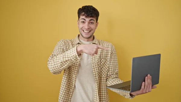 Junger Hispanischer Mann Lächelt Und Zeigt Auf Laptop Vor Isoliertem — Stockfoto