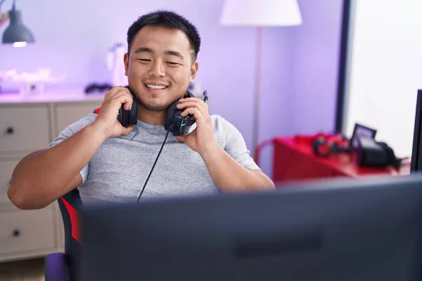 Joven Hombre Chino Streamer Sonriendo Con Confianza Celebración Auriculares Sala —  Fotos de Stock