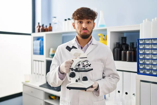 Arab Brodą Pracujący Laboratorium Naukowca Trzymający Mikroskop Przygnębiony Zaniepokojony Strachem — Zdjęcie stockowe
