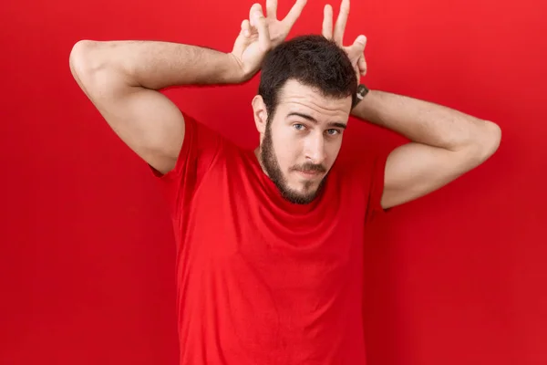 Mladý Hispánec Neformální Červené Tričko Pózuje Legračně Bláznivě Prsty Hlavě — Stock fotografie