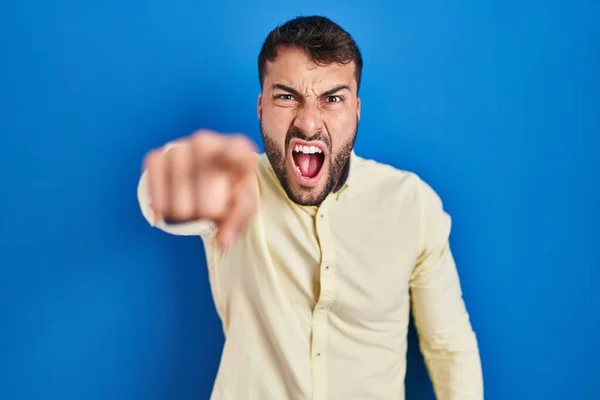 カメラに不満と不満を指摘青い背景の上に立ってハンサムなヒスパニック系の男 怒って あなたと激怒 — ストック写真