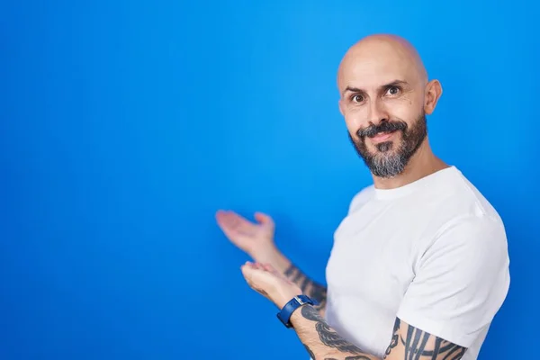 Hispanic Man Tattoos Standing Blue Background Inviting Enter Smiling Natural — Stock Photo, Image