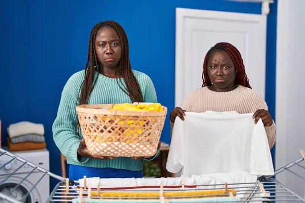 Dwie Afrykańskie Kobiety Wieszające Ubrania Sznurze Przygnębione Martwiące Się Cierpienie — Zdjęcie stockowe