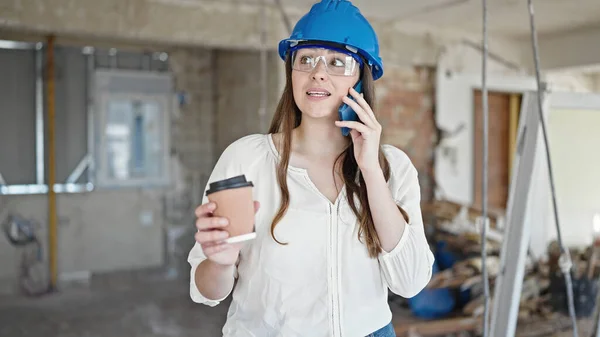 年轻美丽的惊慌失措的女建筑商在建筑工地用智能手机喝咖啡 — 图库照片