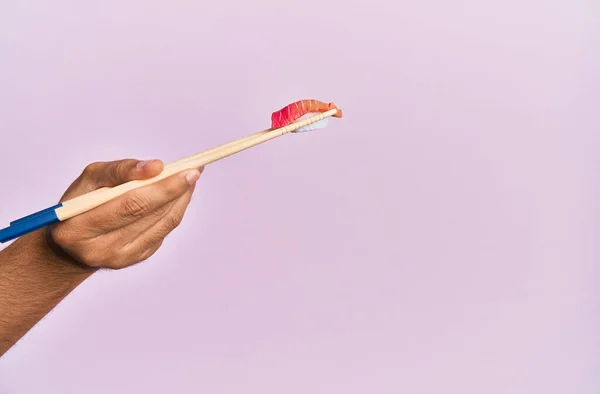 男の手保持マグロ握り箸で隔離されたピンクの背景 — ストック写真