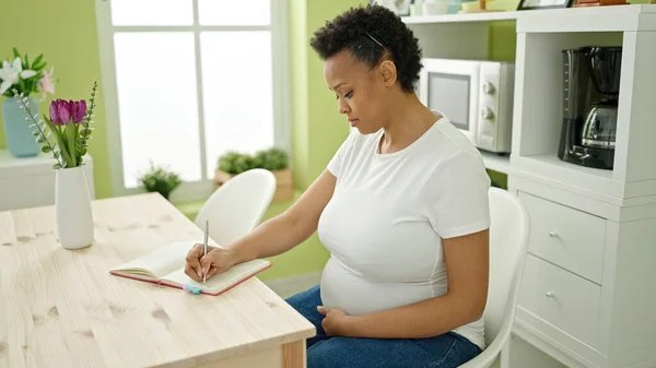 Jonge Zwangere Vrouw Schrijven Notitieboekje Aanraken Buik Bij Eetkamer — Stockfoto