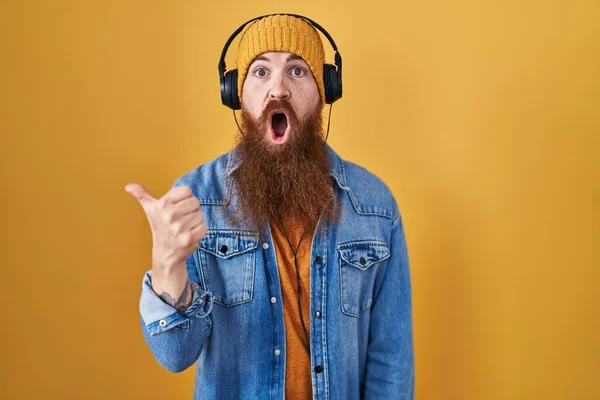 Καυκάσιος Άνδρας Μακριά Γενειάδα Ακούγοντας Μουσική Χρησιμοποιώντας Ακουστικά Έκπληκτος Δείχνοντας — Φωτογραφία Αρχείου